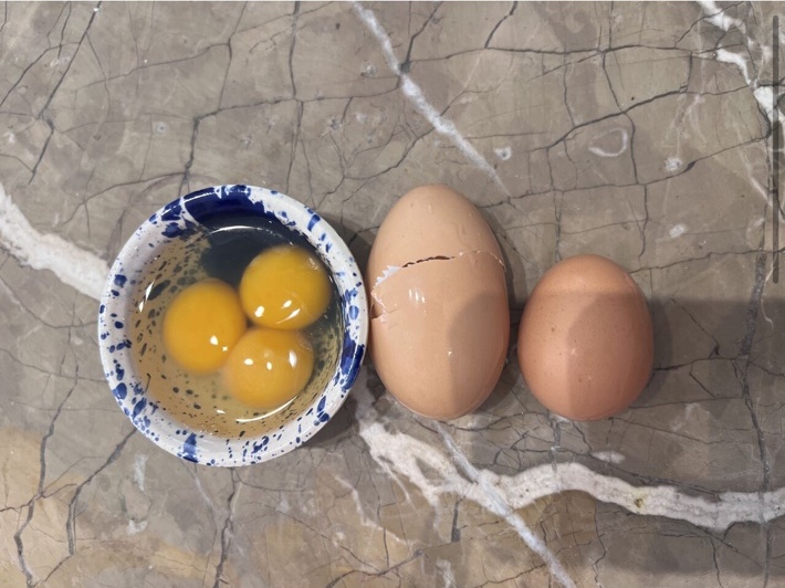 A rare triple-yolk egg from Mallorca beside two whole eggs